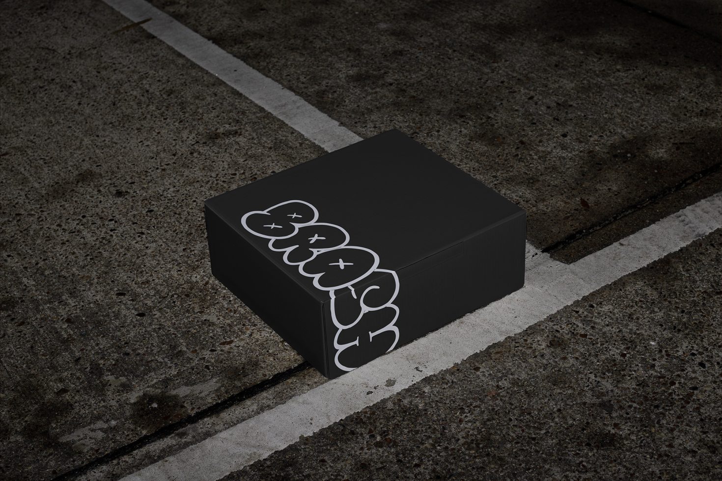 Black box with stylish graffiti font mockup on an urban concrete ground for design presentation.